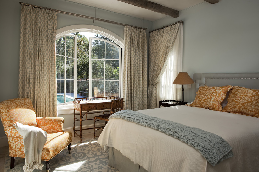 На фото: гостевая спальня среднего размера, (комната для гостей) в средиземноморском стиле с синими стенами, полом из известняка, синим полом и фасадом камина из штукатурки без камина