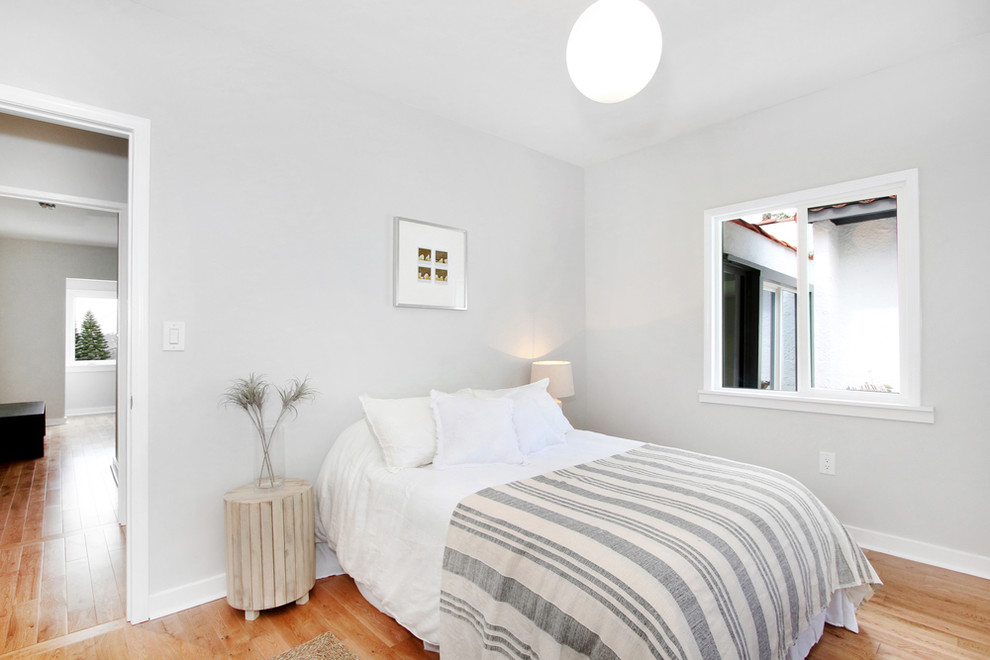 This is an example of a small scandi guest bedroom in Los Angeles with grey walls and light hardwood flooring.