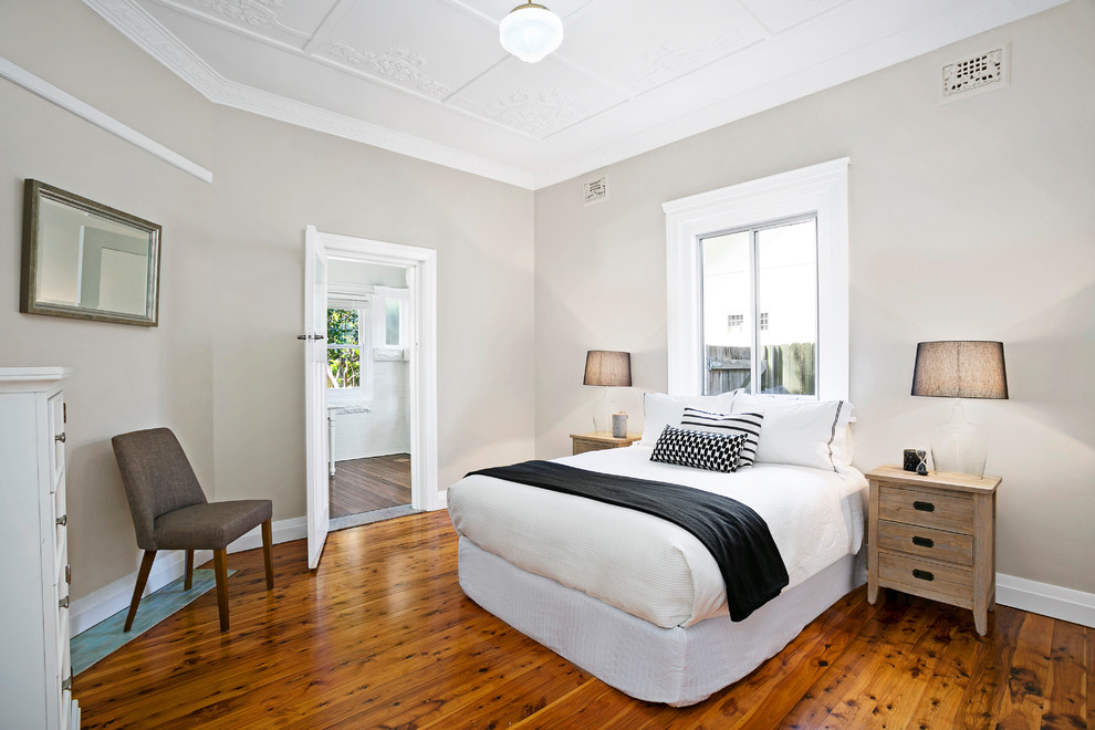 This is an example of a medium sized classic master bedroom in Sydney with beige walls and medium hardwood flooring.
