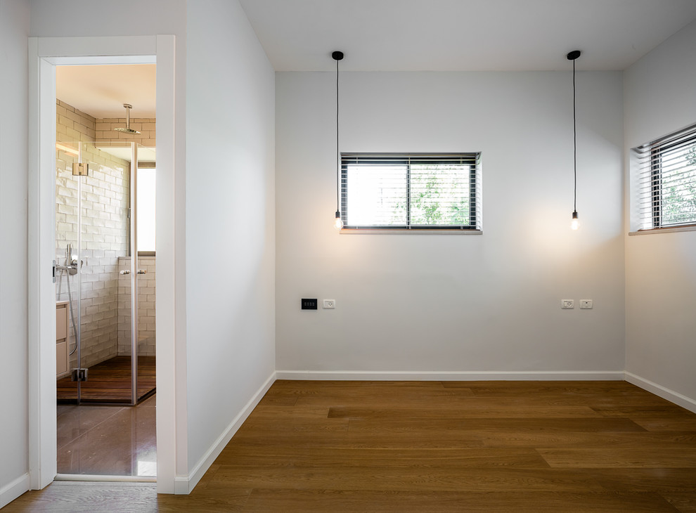 Réalisation d'une petite chambre parentale design avec un mur blanc, un sol en bois brun et un sol marron.