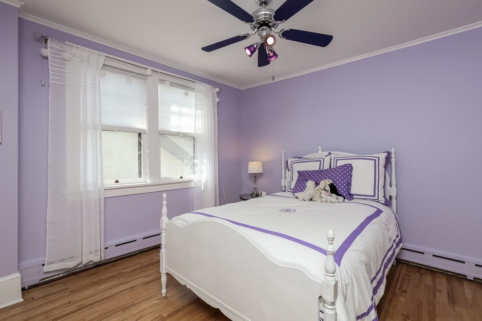 Inspiration pour une chambre craftsman de taille moyenne avec un sol en bois brun et un mur violet.