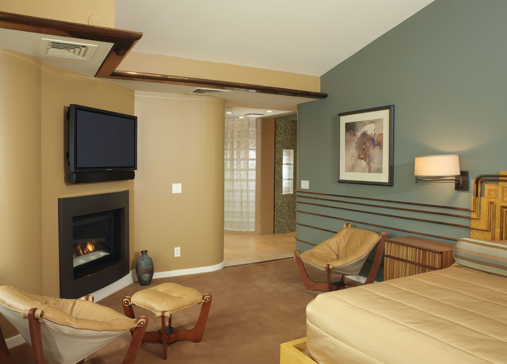 Ejemplo de dormitorio principal moderno grande con paredes verdes, moqueta, chimenea de esquina, marco de chimenea de metal y suelo marrón