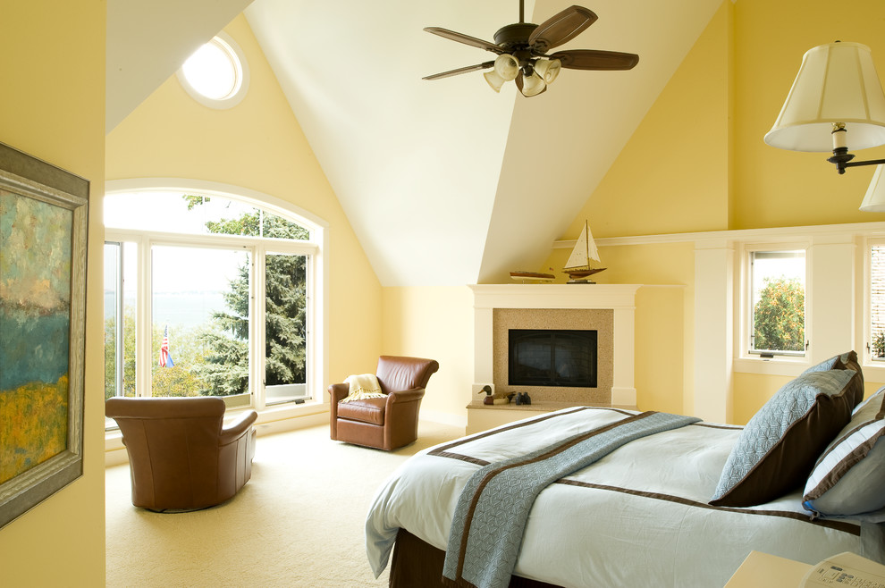 Großes Gästezimmer mit gelber Wandfarbe, Teppichboden, Kamin, Kaminumrandung aus Stein und beigem Boden in Sonstige