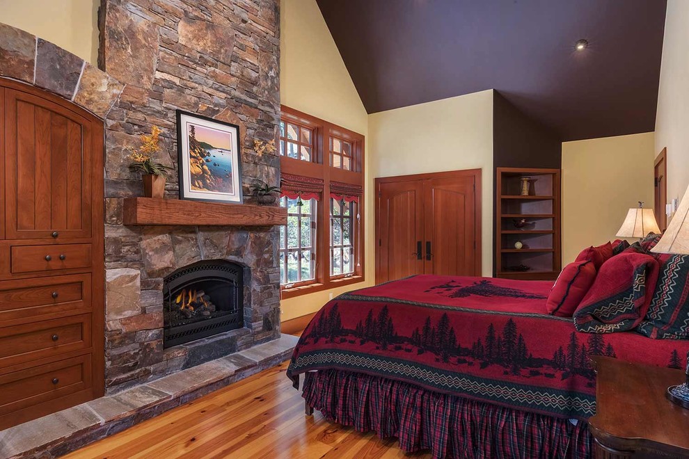 Imagen de habitación de invitados tradicional renovada con todas las chimeneas, marco de chimenea de piedra y suelo de madera clara