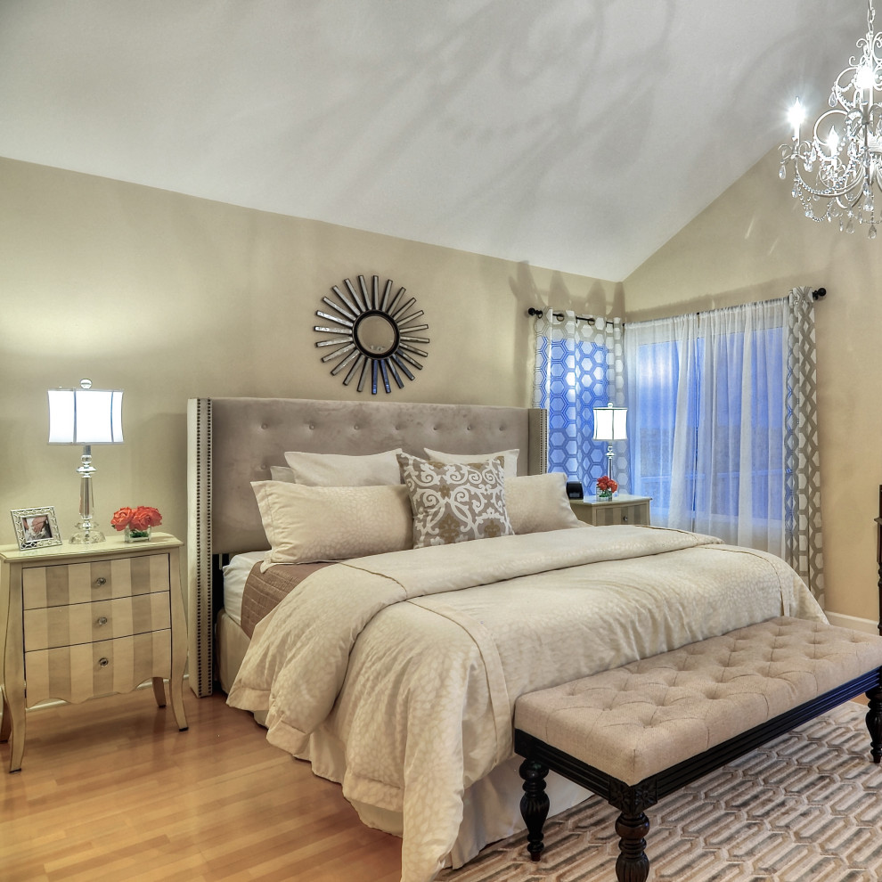 This is an example of a large traditional master bedroom in Orange County with beige walls, light hardwood flooring, brown floors and a vaulted ceiling.