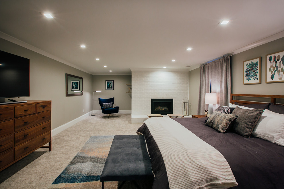 Стильный дизайн: огромная хозяйская спальня в стиле неоклассика (современная классика) с серыми стенами, ковровым покрытием, стандартным камином, фасадом камина из кирпича и серым полом - последний тренд