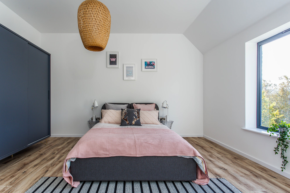 Trendy medium tone wood floor and brown floor bedroom photo in Sussex with white walls