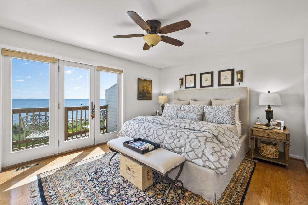 Foto de dormitorio principal costero grande con suelo de madera en tonos medios, paredes grises y suelo marrón
