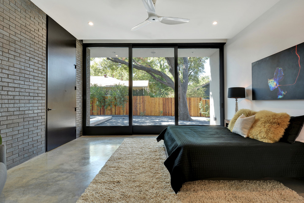 Mittelgroßes Modernes Hauptschlafzimmer ohne Kamin mit weißer Wandfarbe und Betonboden in Austin
