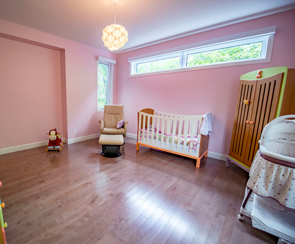 Inspiration pour une chambre de bébé design avec un mur rose et un sol marron.
