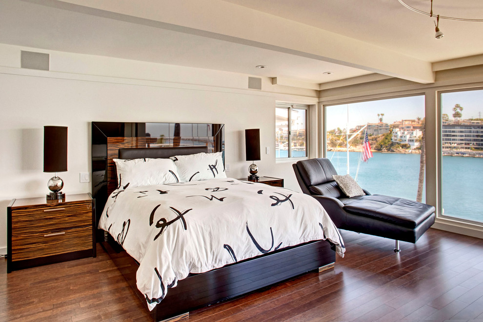 This is an example of a contemporary bedroom in Orange County with white walls and dark hardwood flooring.