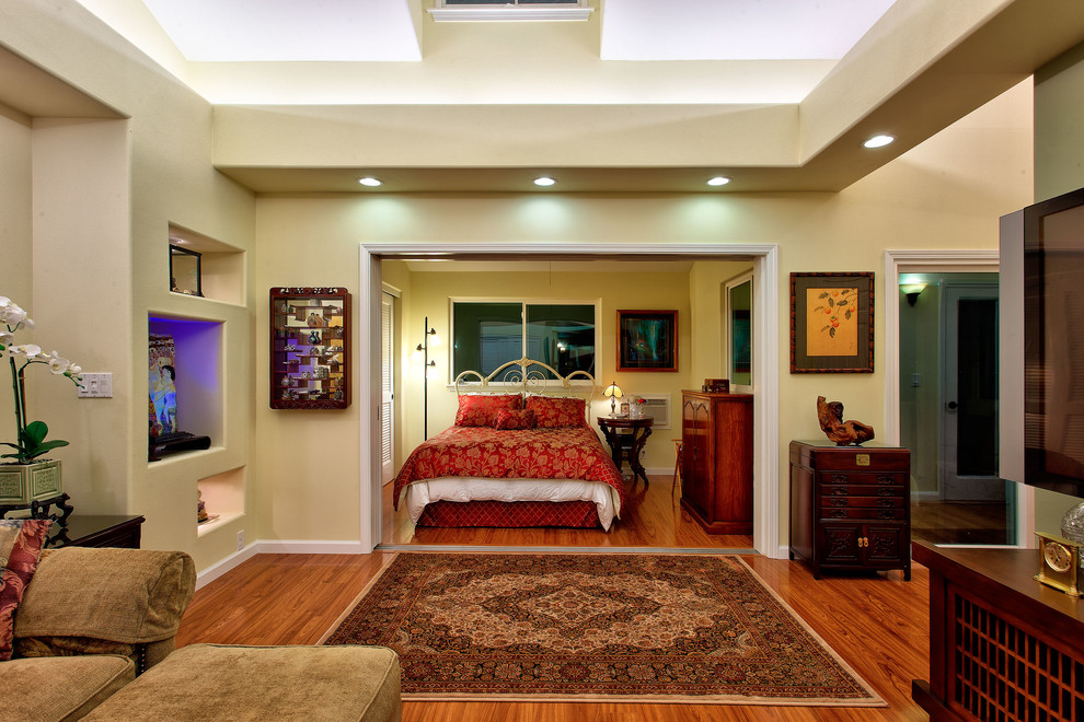 ハワイにある広いアジアンスタイルのおしゃれな主寝室 (黄色い壁、無垢フローリング、暖炉なし、茶色い床)
