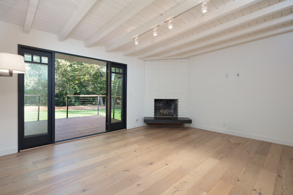 Aménagement d'une chambre parentale campagne de taille moyenne avec un mur blanc, parquet clair, une cheminée d'angle et un manteau de cheminée en brique.
