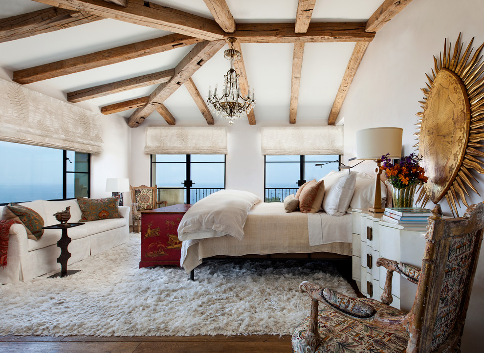 Modelo de dormitorio principal mediterráneo con paredes blancas y suelo de madera en tonos medios