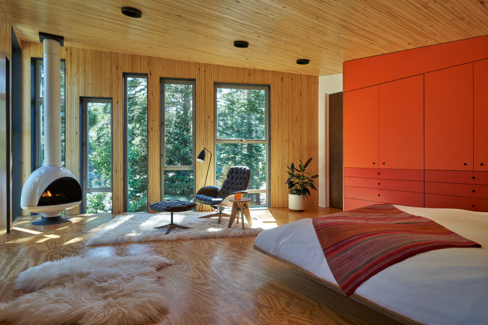 Ejemplo de dormitorio contemporáneo con paredes marrones, suelo de madera en tonos medios, estufa de leña, suelo marrón, madera y madera