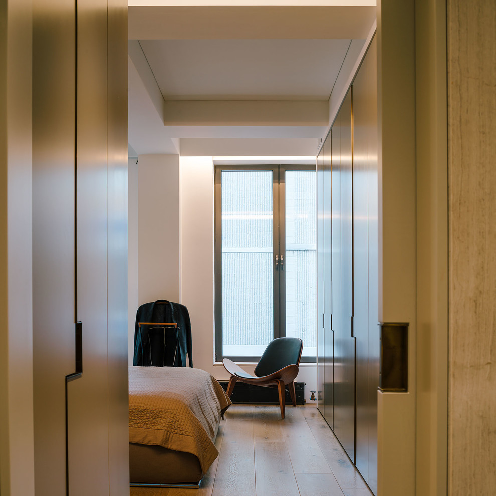Modelo de dormitorio principal minimalista de tamaño medio sin chimenea con paredes blancas, suelo de madera clara y suelo beige