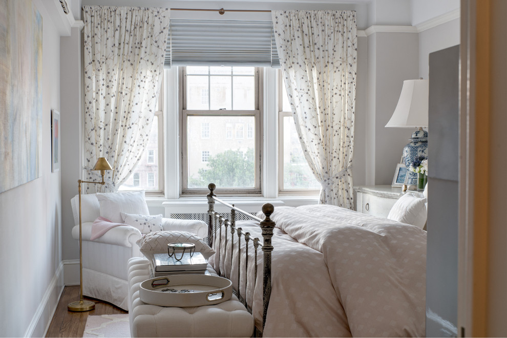 Elegant medium tone wood floor and brown floor bedroom photo in New York with white walls