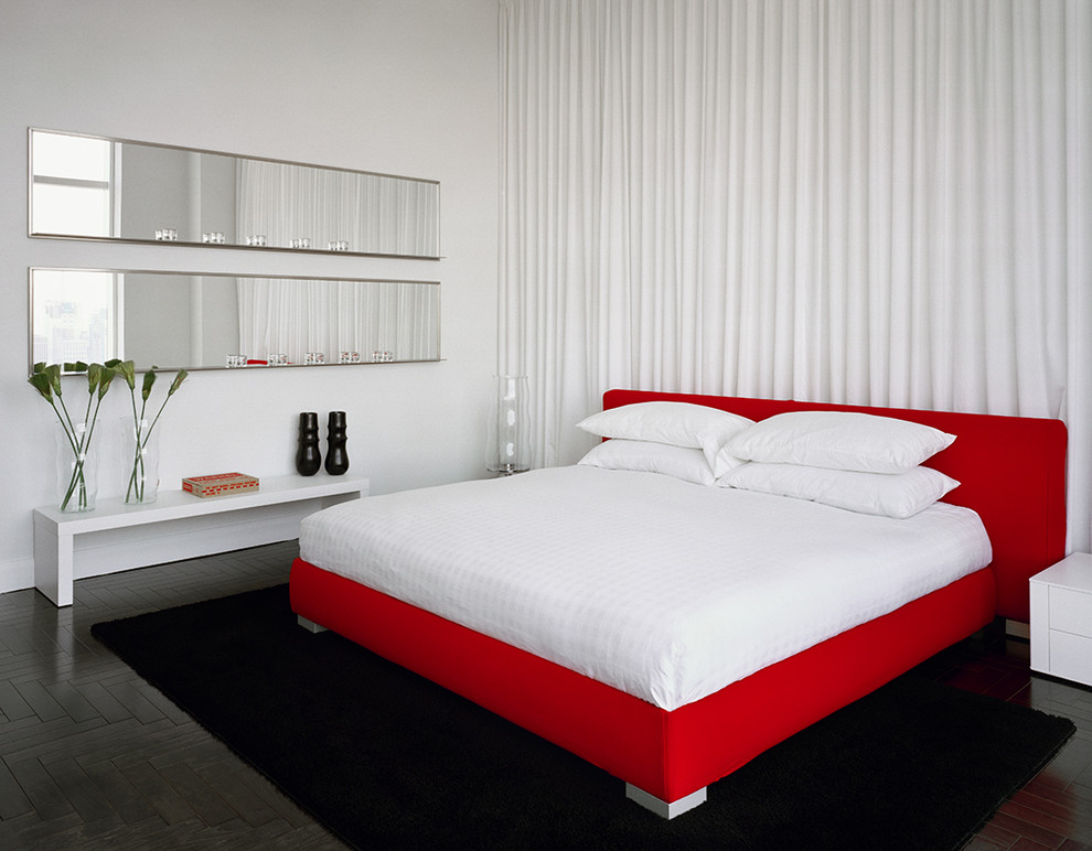 Modelo de dormitorio actual grande con paredes blancas y suelo de madera oscura