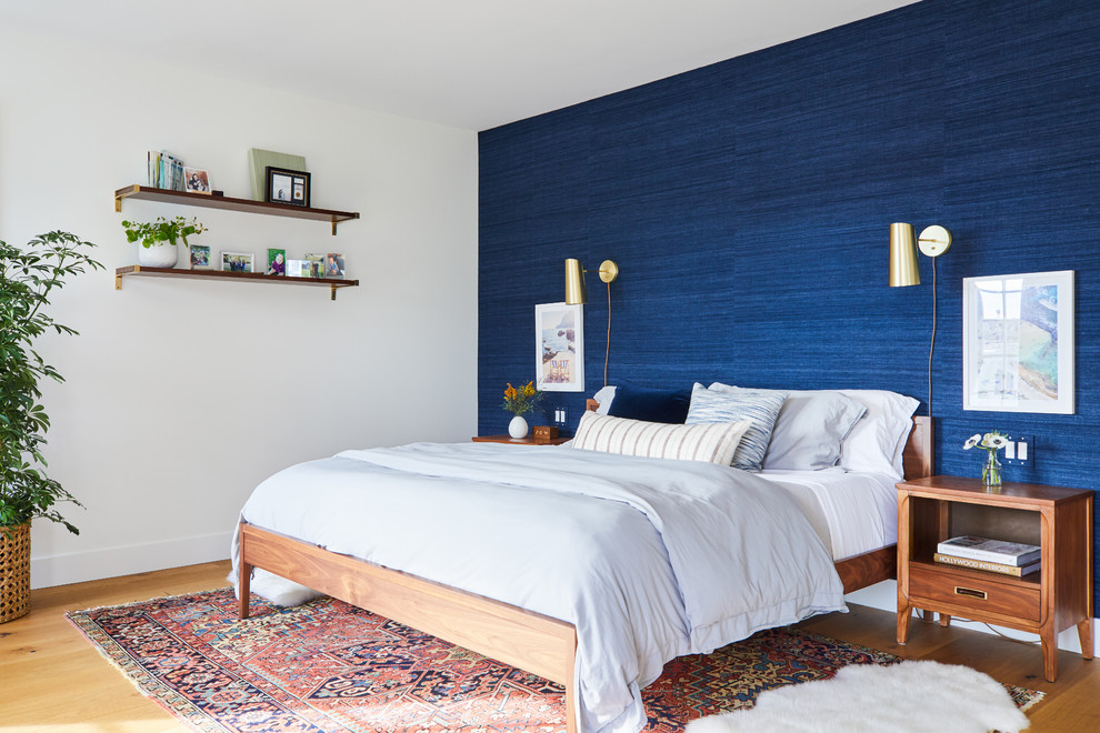 Diseño de dormitorio principal marinero sin chimenea con paredes azules y suelo de madera clara
