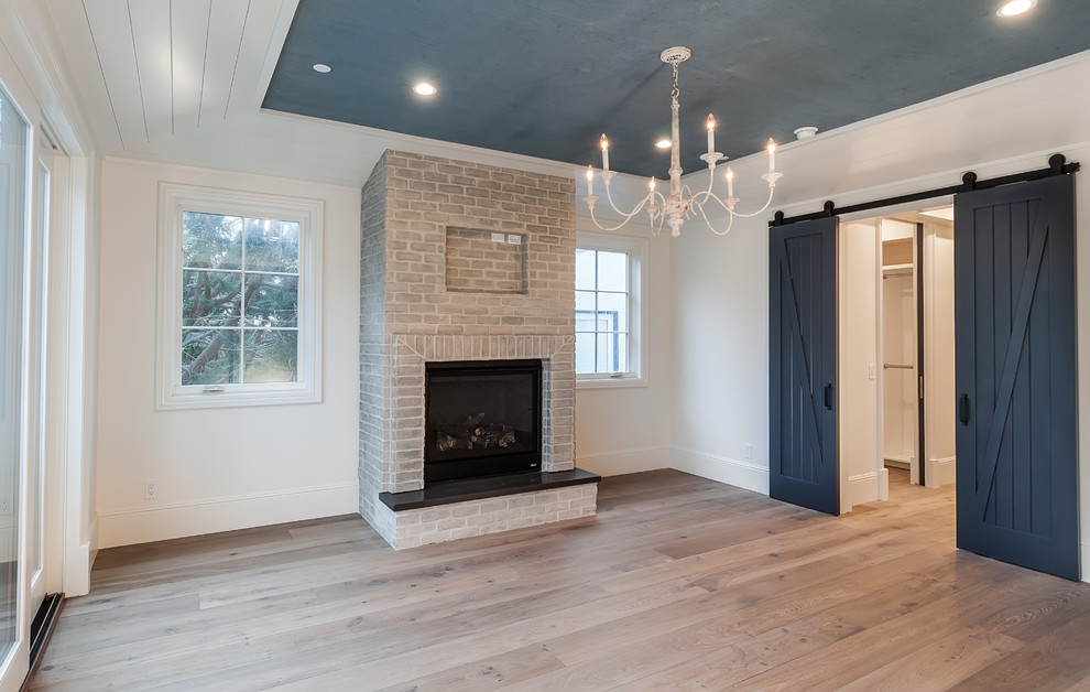 Inspiration for a large farmhouse master light wood floor and brown floor bedroom remodel in Los Angeles with white walls, a standard fireplace and a brick fireplace