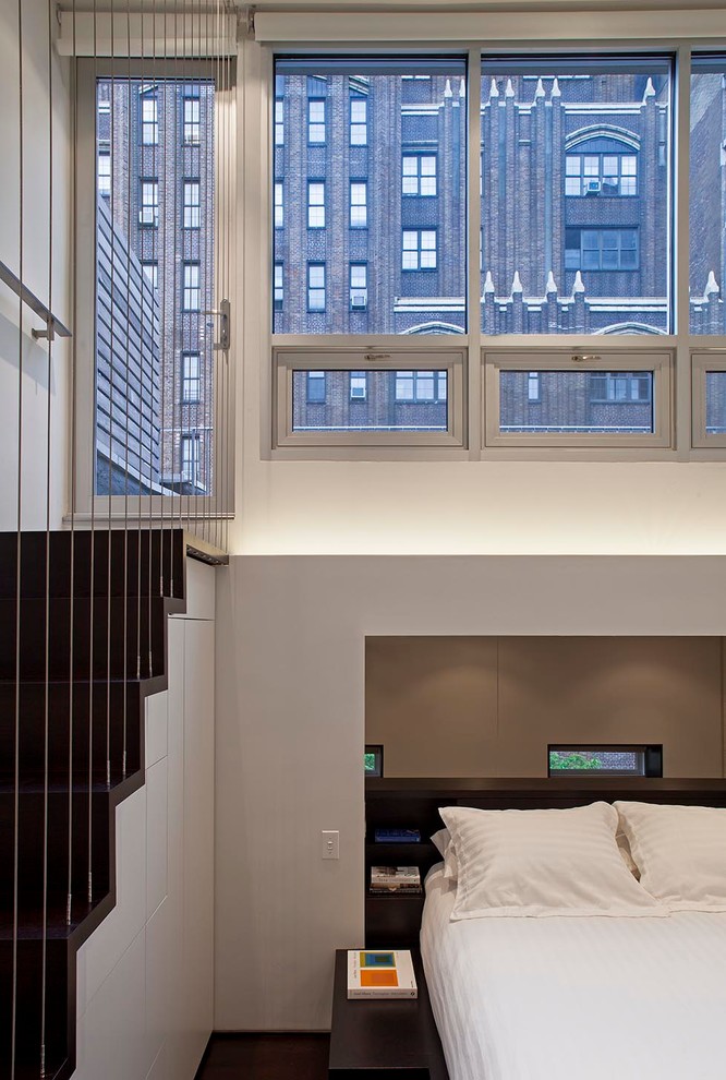 Photo of a small modern mezzanine bedroom in New York with white walls, dark hardwood flooring and no fireplace.