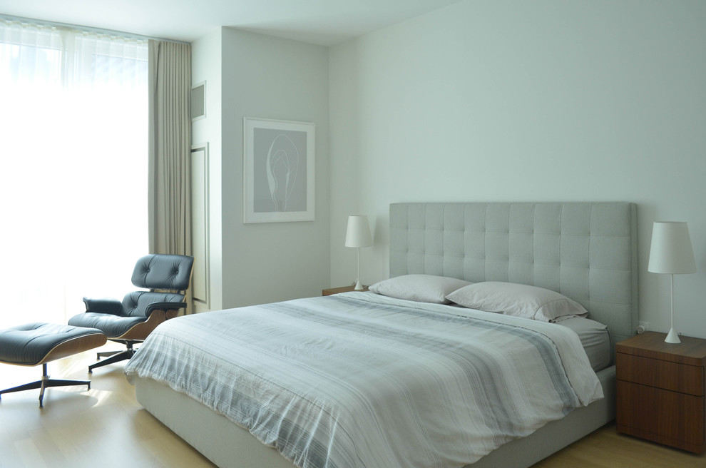 Modelo de dormitorio principal moderno con paredes blancas y suelo de madera clara