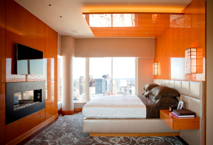 Imagen de dormitorio principal contemporáneo de tamaño medio con parades naranjas, suelo de madera en tonos medios, chimenea lineal y marco de chimenea de metal