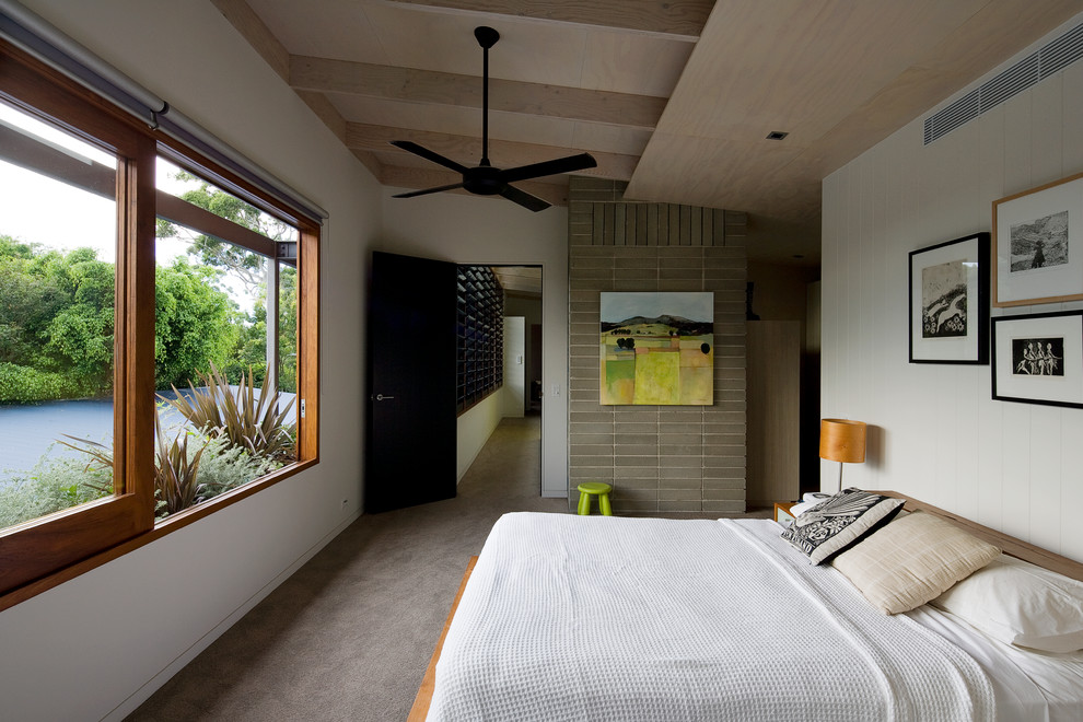 Imagen de dormitorio actual con paredes blancas, moqueta y techo inclinado