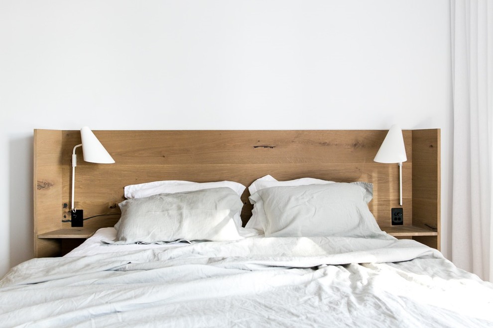 Réalisation d'une grande chambre parentale design avec un mur blanc.