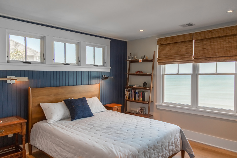 Réalisation d'une chambre parentale marine de taille moyenne avec un mur bleu, un sol en bois brun, un sol marron et du lambris.