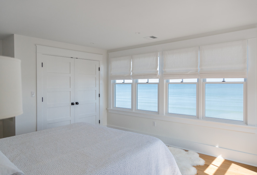 ボストンにある中くらいなビーチスタイルのおしゃれな主寝室 (白い壁、無垢フローリング、茶色い床)