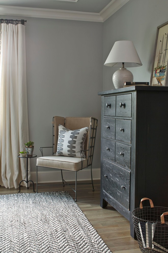 Cette image montre une chambre d'amis rustique de taille moyenne avec un mur gris, un sol en bois brun et aucune cheminée.