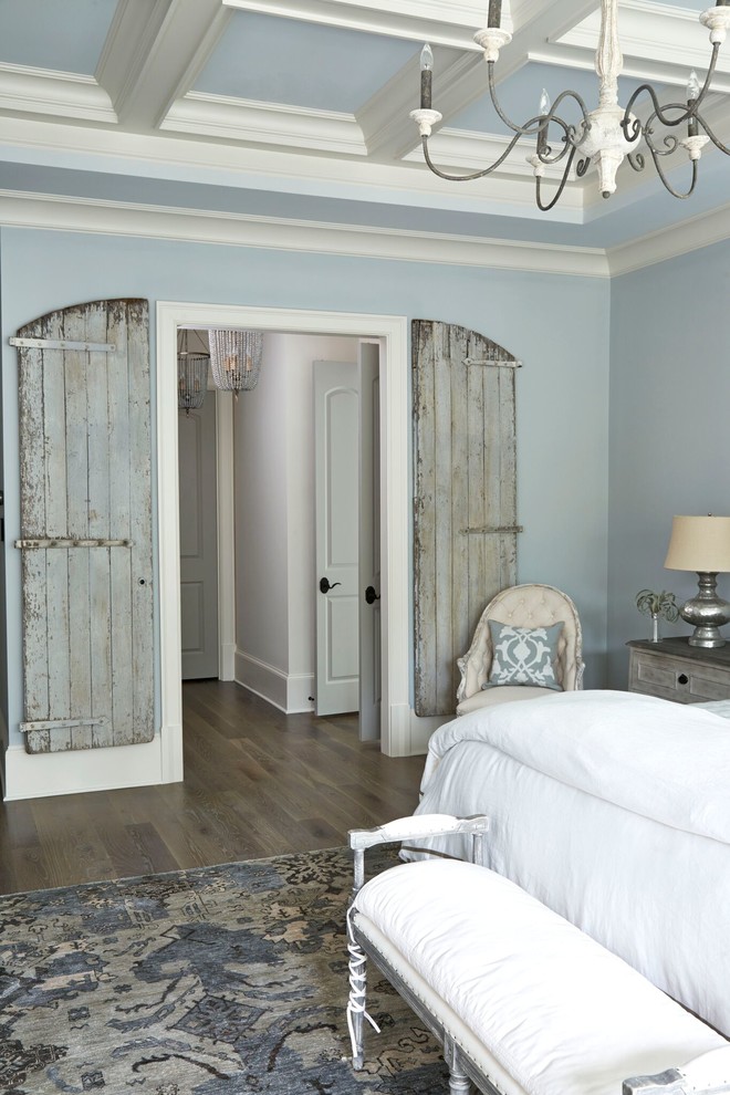 Modelo de dormitorio principal campestre grande sin chimenea con paredes azules y suelo de madera en tonos medios