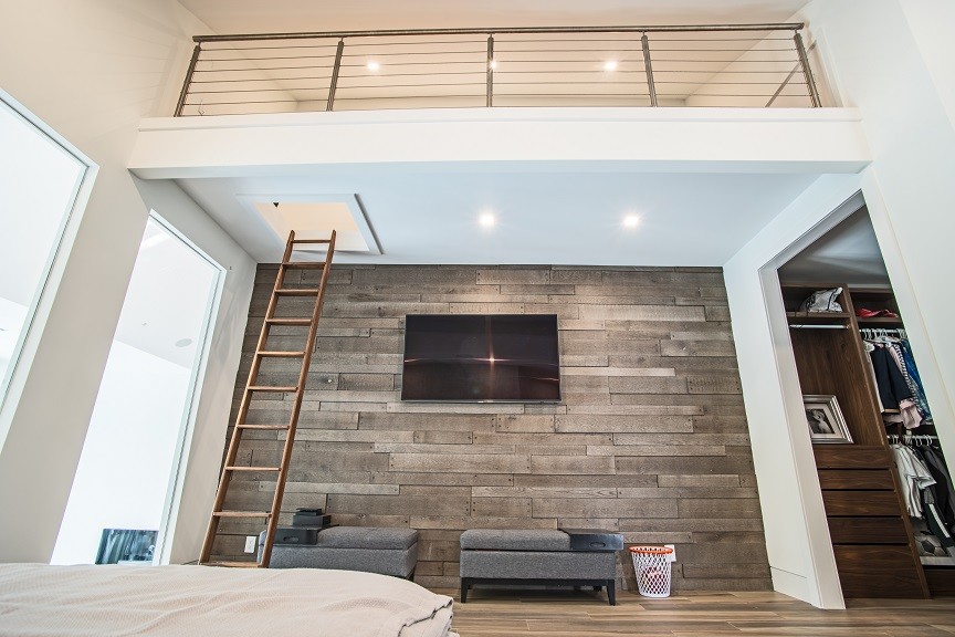 Modelo de dormitorio tipo loft actual de tamaño medio sin chimenea con paredes blancas, suelo de madera clara y suelo marrón