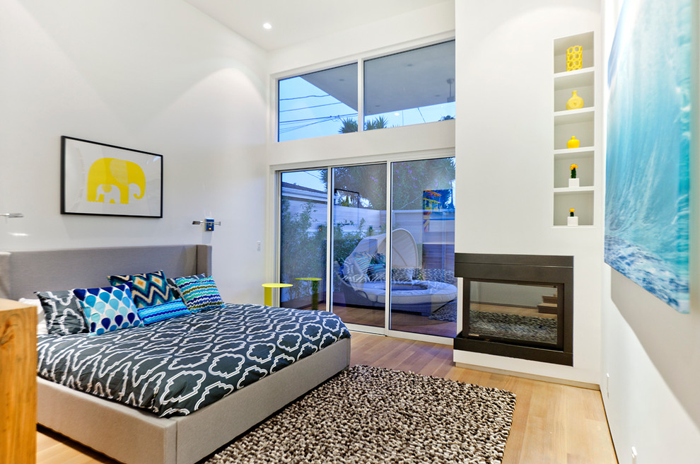 This is an example of a contemporary grey and brown bedroom in Los Angeles with a corner fireplace.