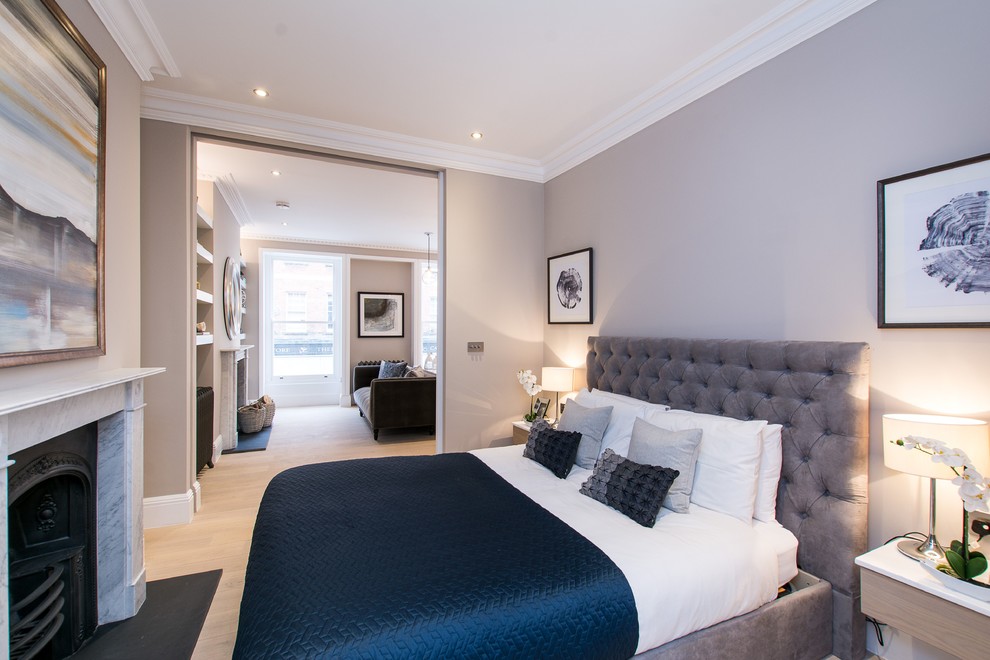 Kleines Modernes Hauptschlafzimmer mit grauer Wandfarbe, hellem Holzboden, Kaminofen, Kaminumrandung aus Stein und braunem Boden in London