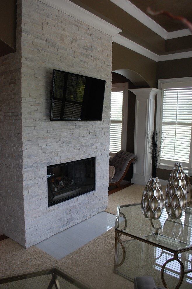 Cette photo montre une chambre chic de taille moyenne avec un mur beige, une cheminée double-face et un manteau de cheminée en pierre.