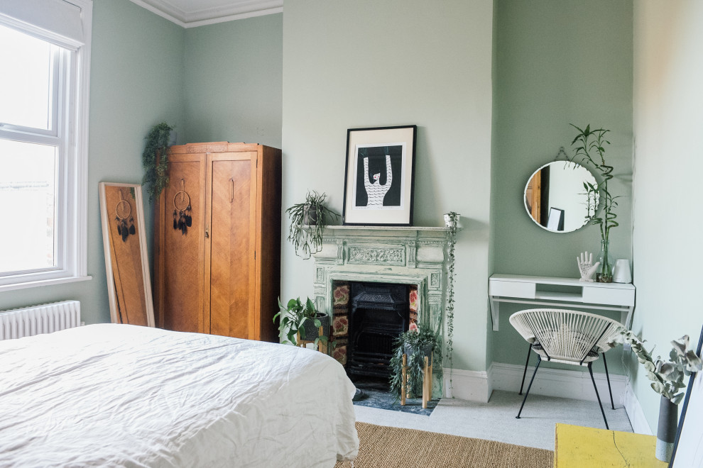 Foto på ett mellanstort minimalistiskt huvudsovrum, med gröna väggar, heltäckningsmatta, en standard öppen spis, en spiselkrans i metall och beiget golv