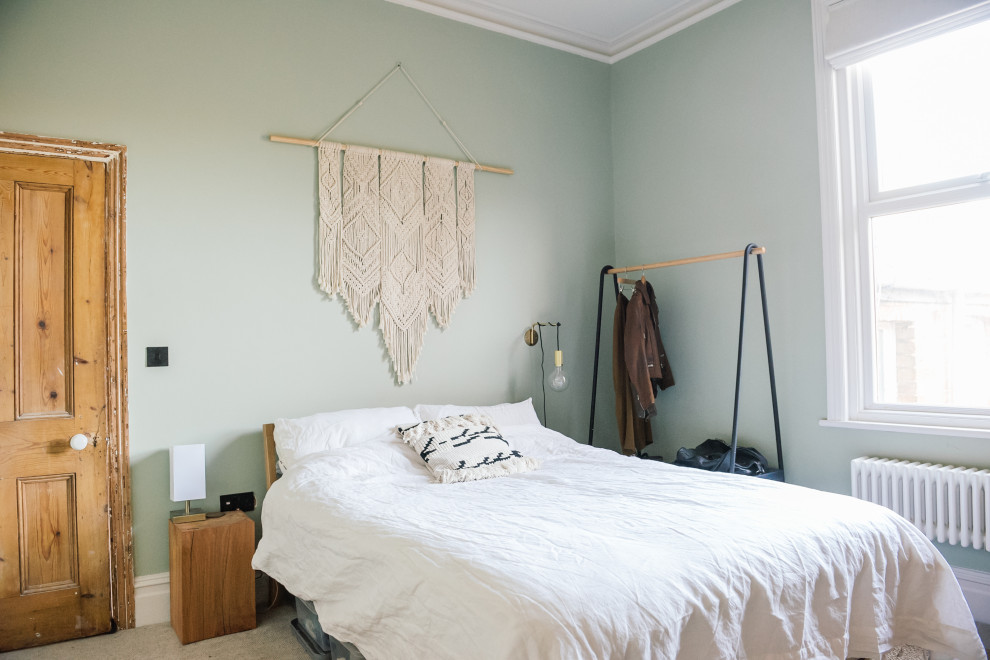 Idée de décoration pour une chambre nordique de taille moyenne avec un mur vert, une cheminée standard, un manteau de cheminée en métal et un sol beige.