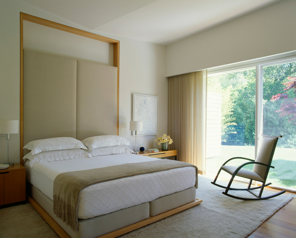 Immagine di una camera matrimoniale contemporanea con pareti beige e pavimento in legno massello medio