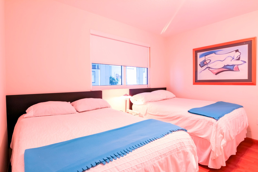 Esempio di una camera degli ospiti tropicale di medie dimensioni con pareti bianche e parquet chiaro