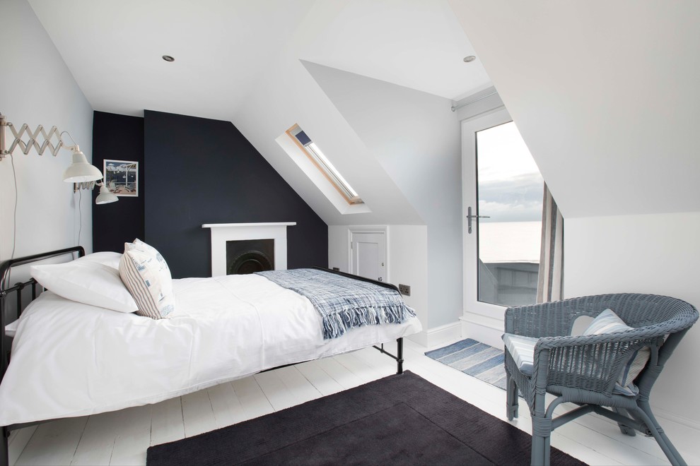 Imagen de dormitorio principal costero grande con paredes blancas, suelo de madera pintada, todas las chimeneas, marco de chimenea de metal y suelo blanco