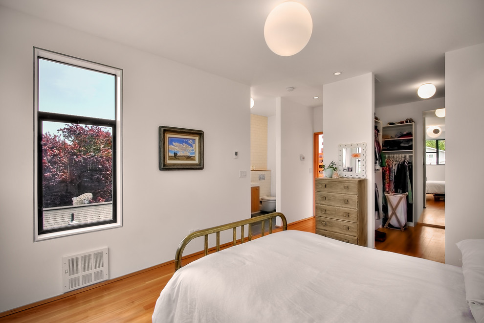 Modelo de dormitorio minimalista con paredes blancas y suelo de madera en tonos medios