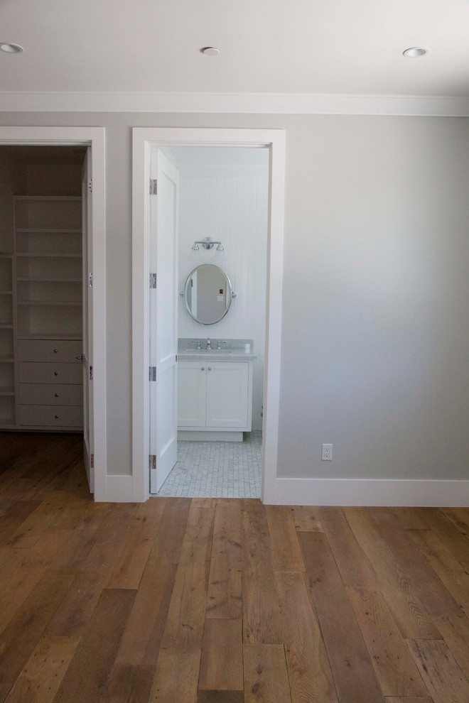 Photo of a large coastal guest bedroom in Los Angeles with grey walls and medium hardwood flooring.
