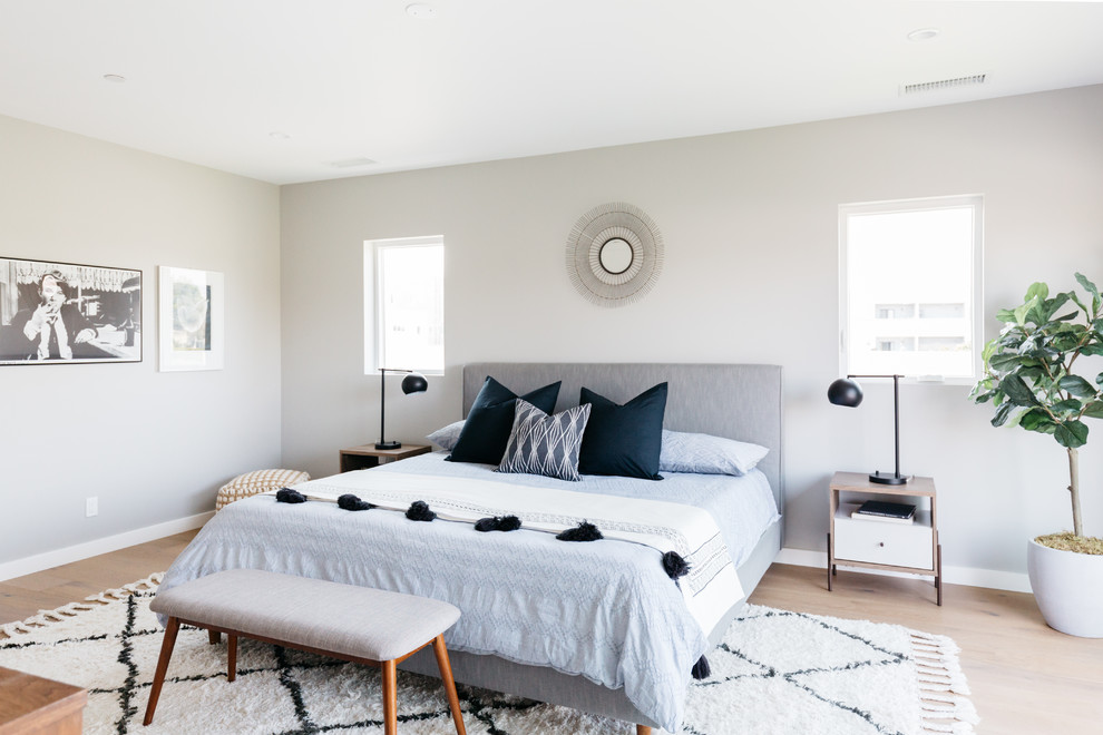 Contemporary bedroom in Los Angeles with grey walls, medium hardwood flooring and brown floors.