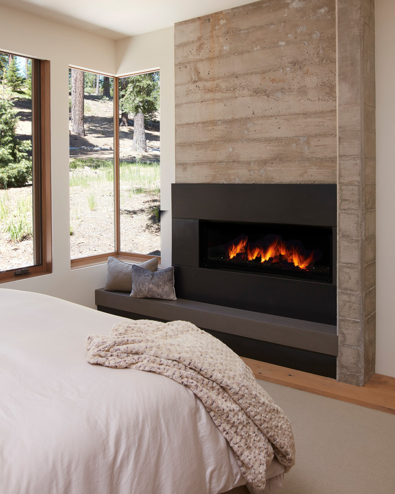 Aménagement d'une chambre parentale contemporaine de taille moyenne avec un manteau de cheminée en béton, une cheminée ribbon, un mur blanc, un sol en bois brun et un sol marron.