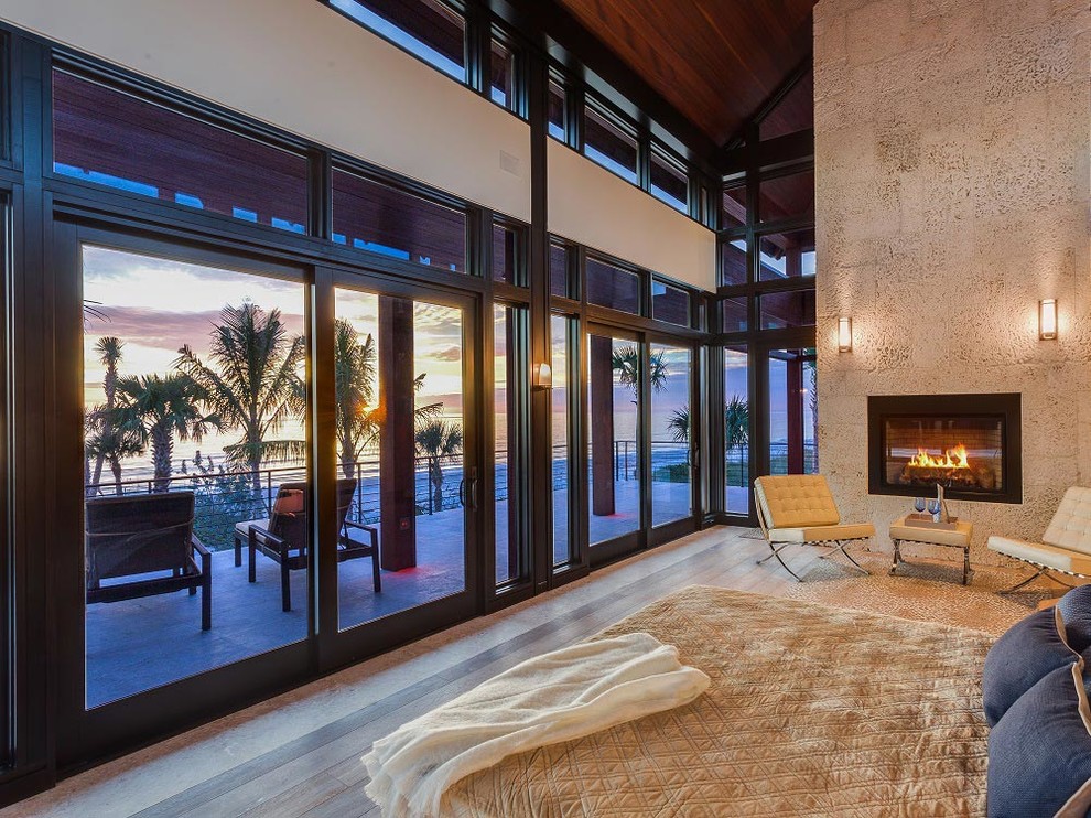 Großes Modernes Hauptschlafzimmer mit beiger Wandfarbe, braunem Holzboden, Kamin und gefliester Kaminumrandung in Orange County