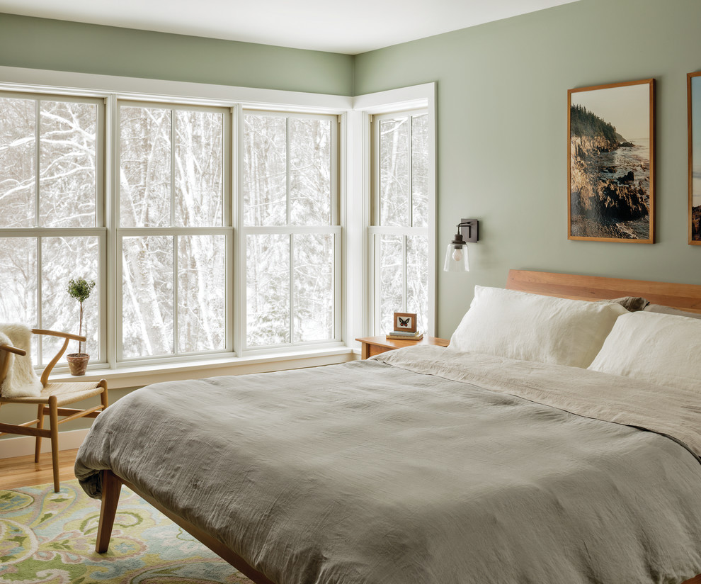 This is an example of a medium sized classic bedroom in Portland Maine with green walls and light hardwood flooring.