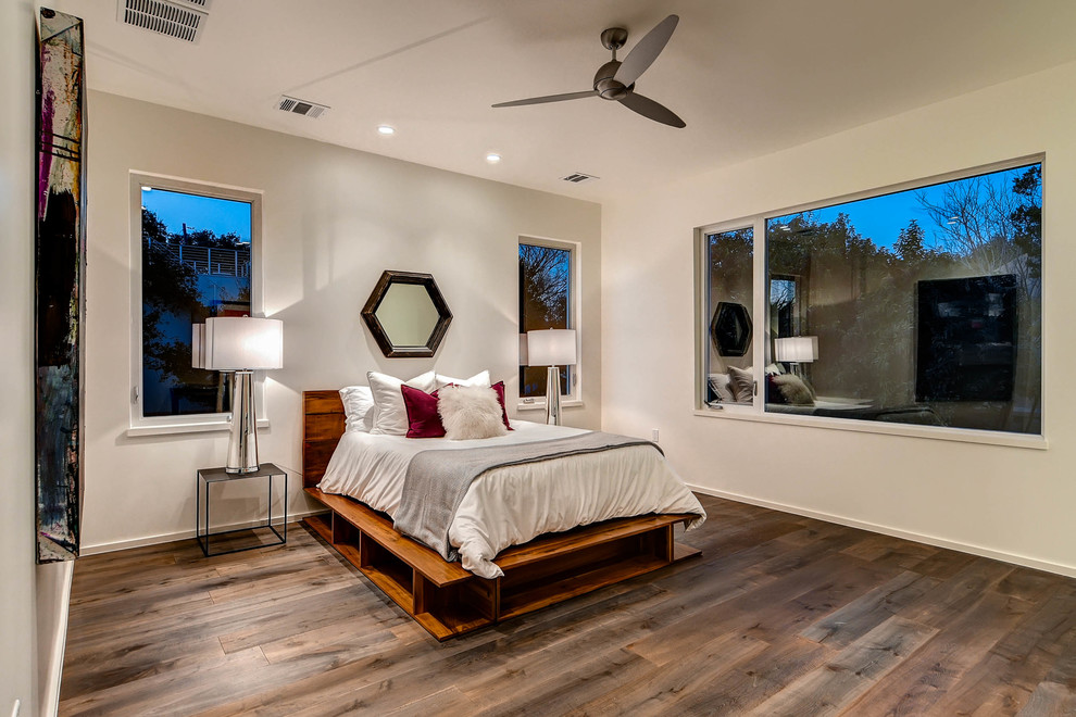 Modelo de habitación de invitados actual grande sin chimenea con paredes blancas y suelo de madera en tonos medios