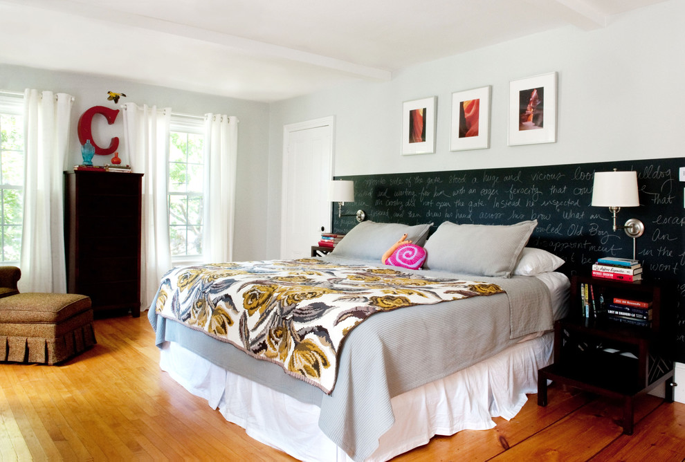 Example of an eclectic medium tone wood floor bedroom design in Boston with white walls